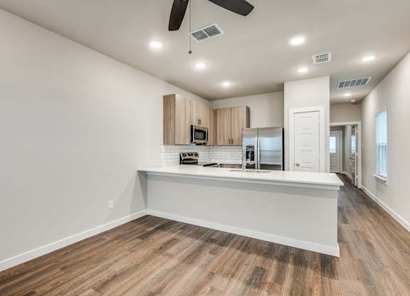 A spacious kitchen with wooden floors and white walls.