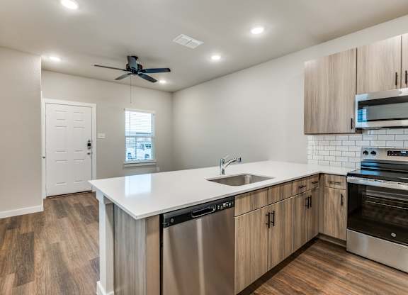 A modern kitchen with wooden floors and stainless steel appliances.