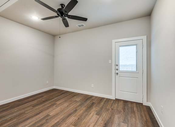 A room with a ceiling fan and a door.