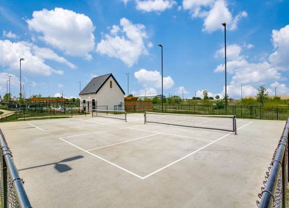 A tennis court with a small building in the background.