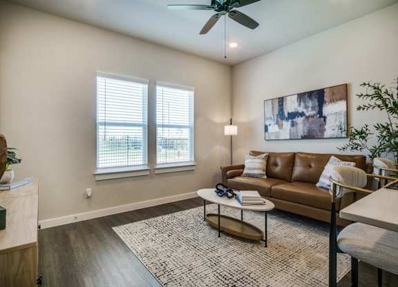 A living room with a brown couch and a ceiling fan.