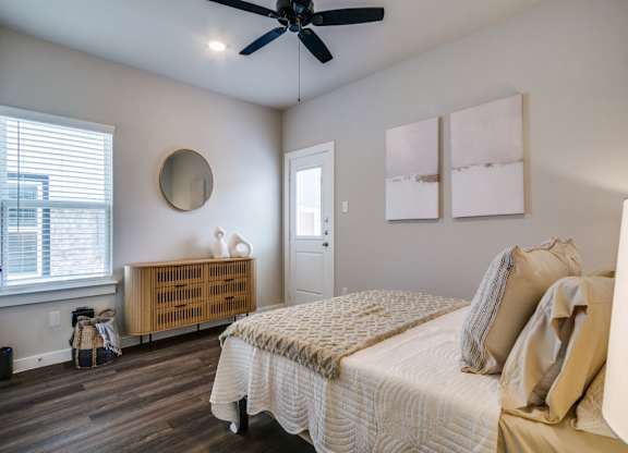 A bedroom with a bed, a ceiling fan, and a window with blinds.