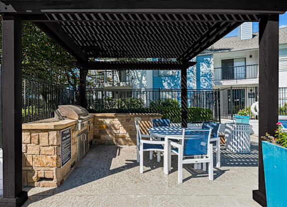 A patio with a table and chairs under a black pergola.