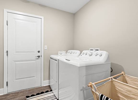 a utility room with a washer and dryer and a door to a bathroom