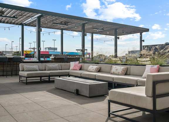 A patio with a white couch and a grey couch with a table in between.