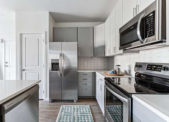 A kitchen with a refrigerator, microwave, and oven.