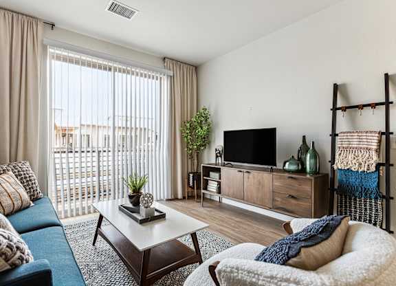 A living room with a blue couch, a white chair, and a wooden coffee table.