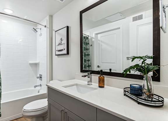 A bathroom with a toilet, sink, and mirror.