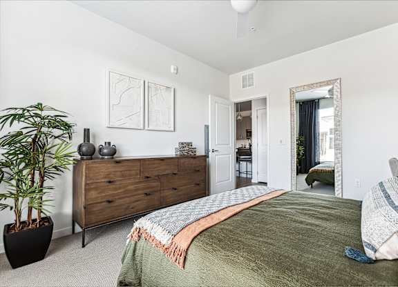 A bedroom with a bed, dresser, and mirror.