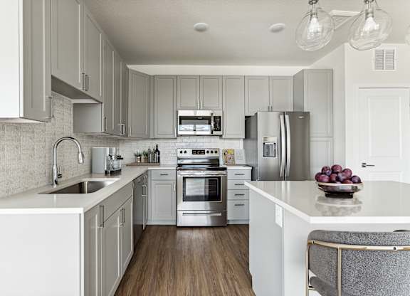 A modern kitchen with white cabinets and stainless steel appliances.