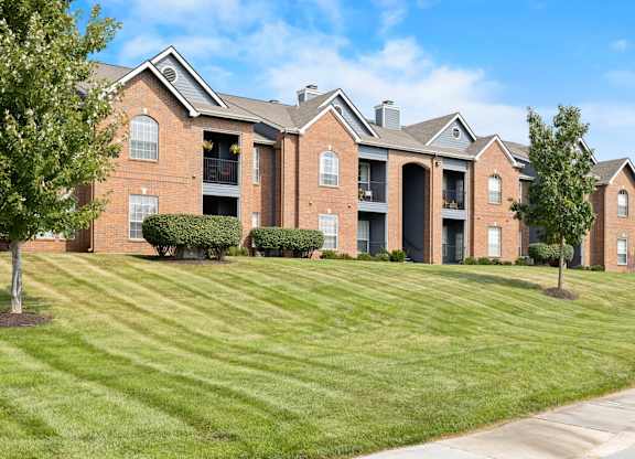 A large brick building with a green lawn in front.