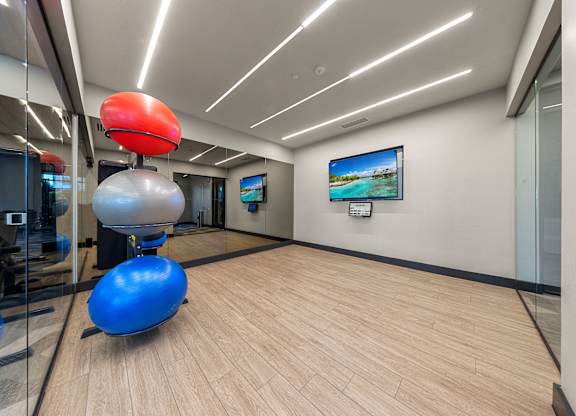 A room with a blue exercise ball and a red exercise ball on a wooden floor.