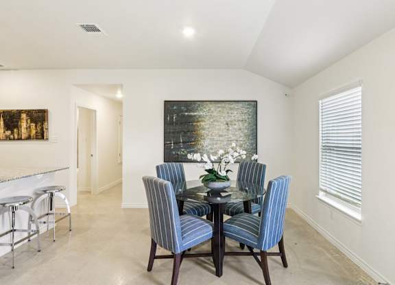 A dining room with a glass table and blue striped chairs.