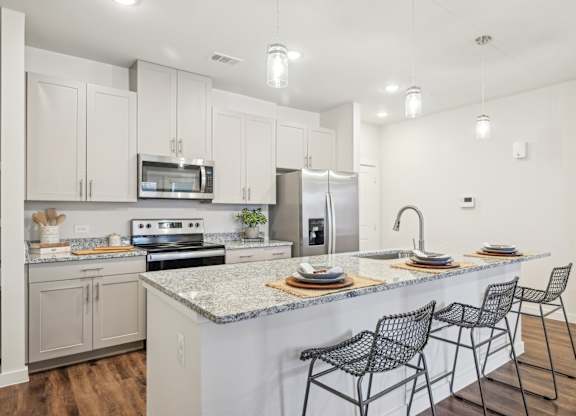 A kitchen with a white counter top and black chairs.
