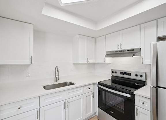 A white kitchen with a black oven and stove top.
