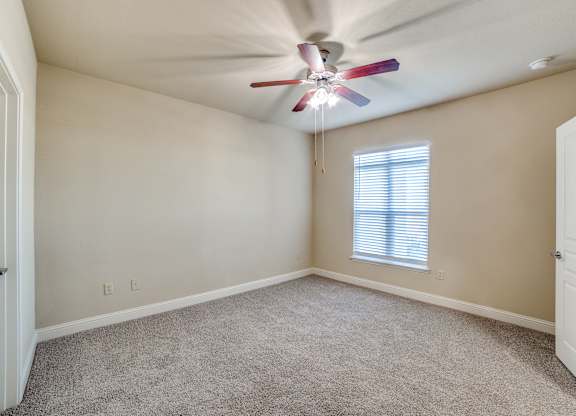 an empty room with a ceiling fan and a window