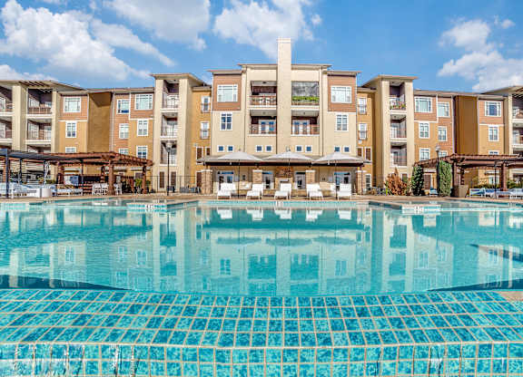A large swimming pool in front of apartment buildings.