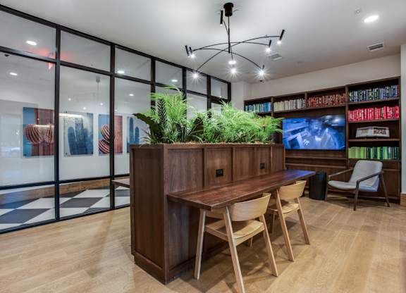 A room with a wooden table and chairs, a potted plant, and a bookshelf filled with books.