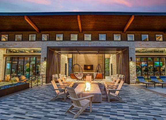 A modern outdoor seating area with a fireplace and chairs.