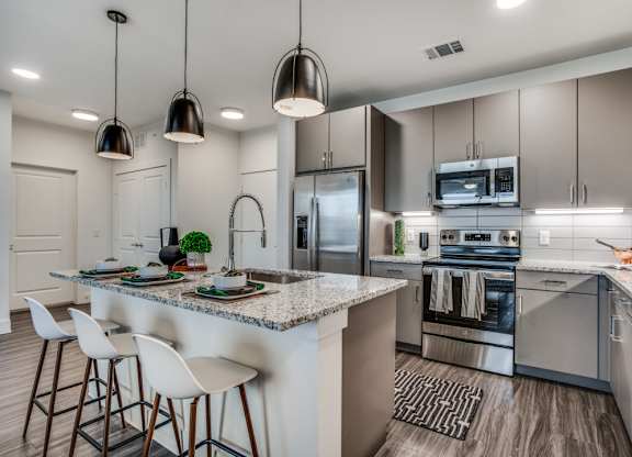 A modern kitchen with a granite countertop and stainless steel appliances.