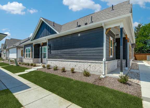 A modern house with a grey front yard.