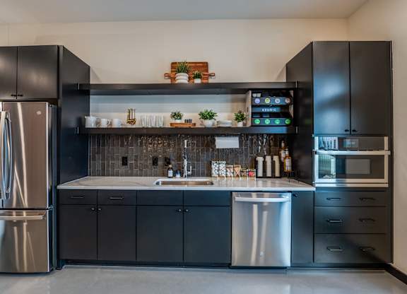 A modern kitchen with black cabinets and stainless steel appliances.