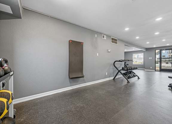 A gym with a grey floor and a row of exercise equipment.