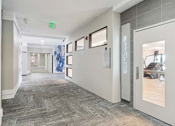 A hallway with a carpeted floor and a white door on the right.