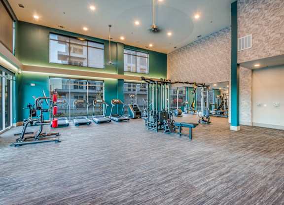 A gym with a variety of equipment including treadmills, weights, and exercise machines.
