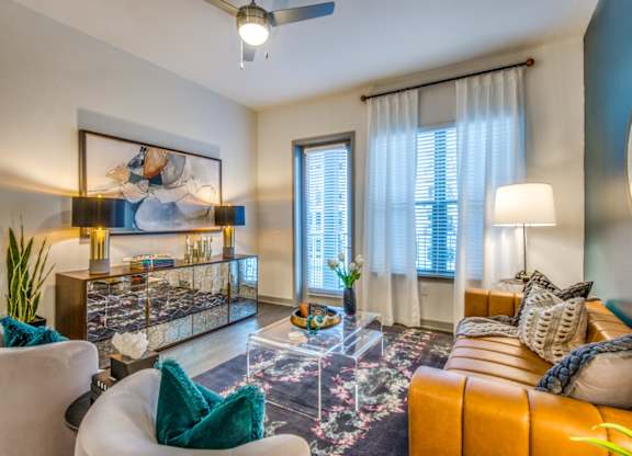 A living room with a white sofa, a glass coffee table, and a painting on the wall.