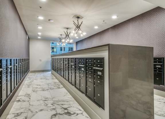A long hallway with a marble floor and a wall of elevators.
