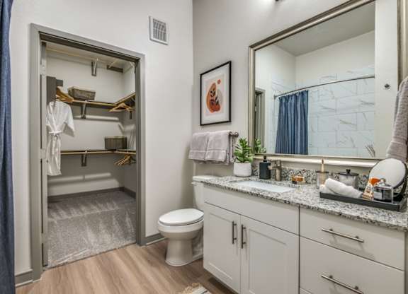 A bathroom with a toilet, sink, and mirror.