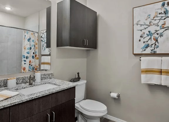 A bathroom with a toilet, sink, and a painting on the wall.