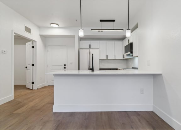 an empty kitchen with white cabinets and a white counter top