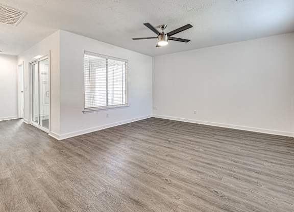 A room with a ceiling fan and a window with blinds.