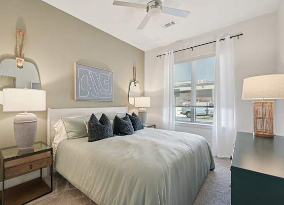 A bedroom with a bed, nightstand, and a window with curtains.