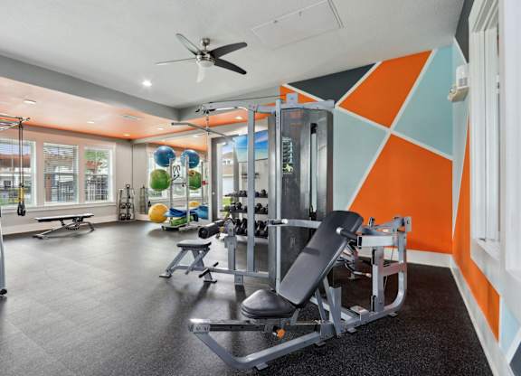 A gym with orange and blue walls and a variety of equipment.