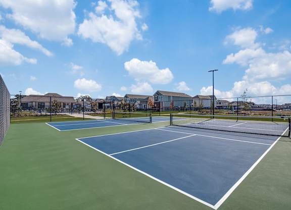A tennis court with a blue sky and clouds in the background.