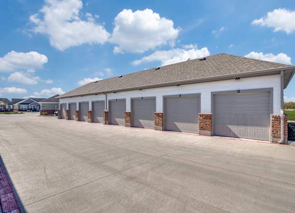 A large building with a grey roof and white walls has a row of garage doors.