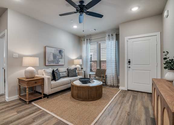 A living room with a white couch, a round coffee table, and a ceiling fan.