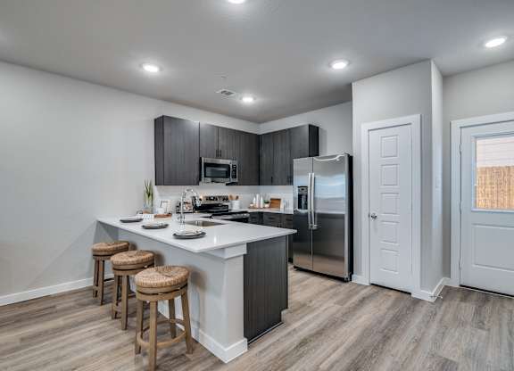 A modern kitchen with a white island and wooden stools.