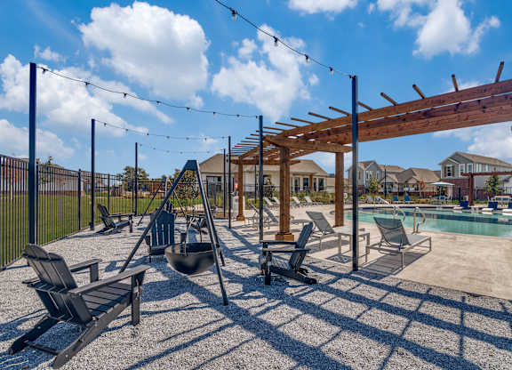 A sunny day at the pool with a wooden pergola and lounge chairs.