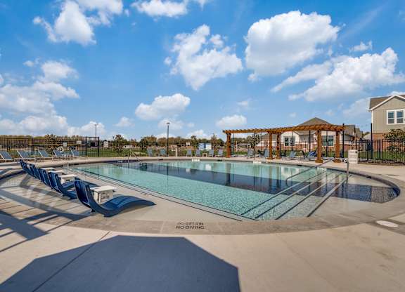 A large outdoor swimming pool with a slide and a gazebo in the background.