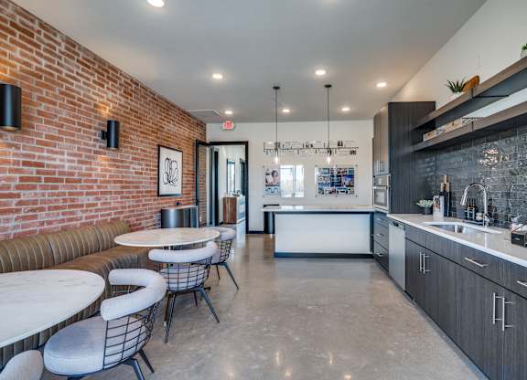 A modern kitchen with a bar area and a dining table with chairs.