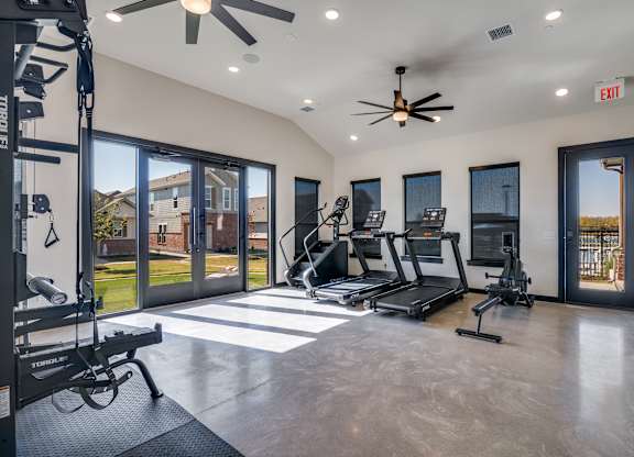 A spacious home gym with a treadmill, elliptical machines, and a weight bench.