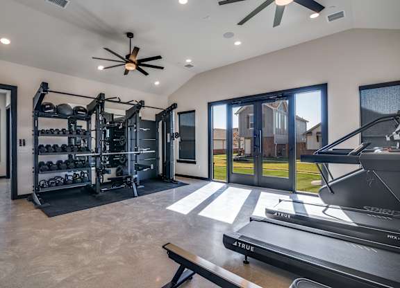 A modern home gym with a treadmill, weights, and exercise equipment.