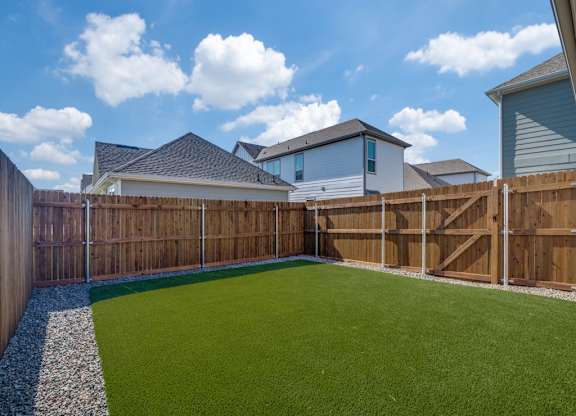 A backyard with a green lawn and a wooden fence.