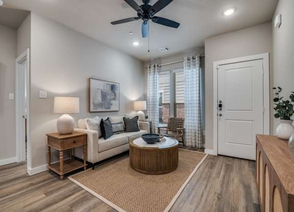 A living room with a couch, a coffee table, and a ceiling fan.