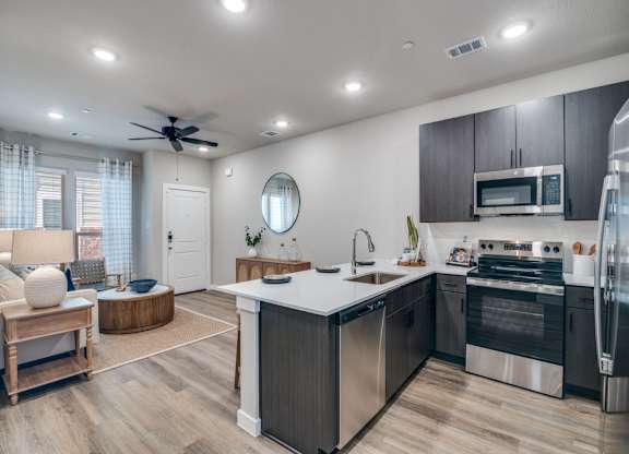 A modern kitchen with stainless steel appliances and wooden flooring.