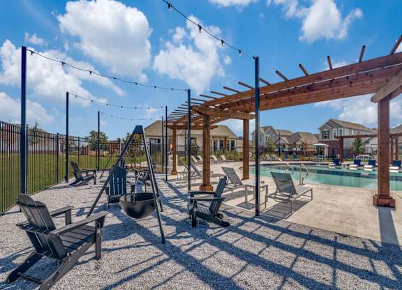 A sunny day at the poolside with chairs and a pergola.